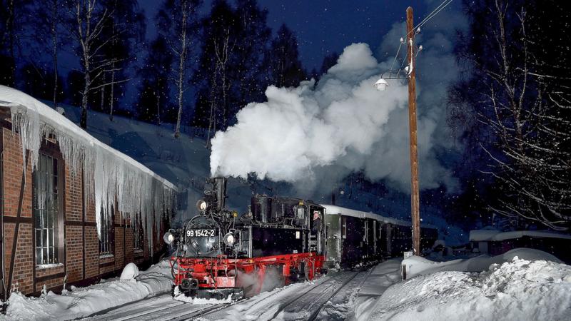In den Morgenstunden des 15. Januars 2017 startete eine privat organisierte Fotoveranstaltung – im Blitzlicht fährt die IV K 99 1542-2 am winterlichen Jöhstädter Lokschuppen vorbei.