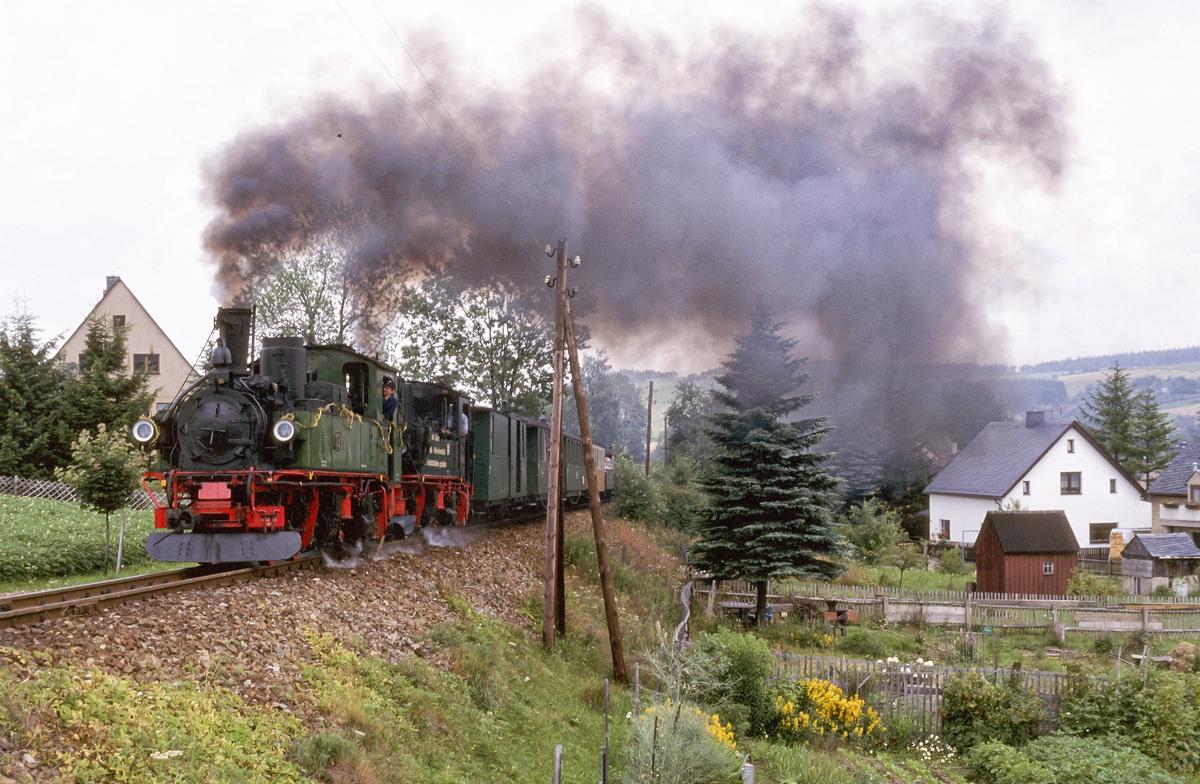 Als diese Strecke von Cranzahl zum Kurort Oberwiesenthal im Juli 1997 ihr 100-jähriges Bestehen feierte, war dieser mit den sächsischen IV K 99 1539-8 aus Radebeul und 99 1590-1 aus Jöhstadt bespannte Zug in der Ortslage Hammerunterwiesenthal unterwegs.