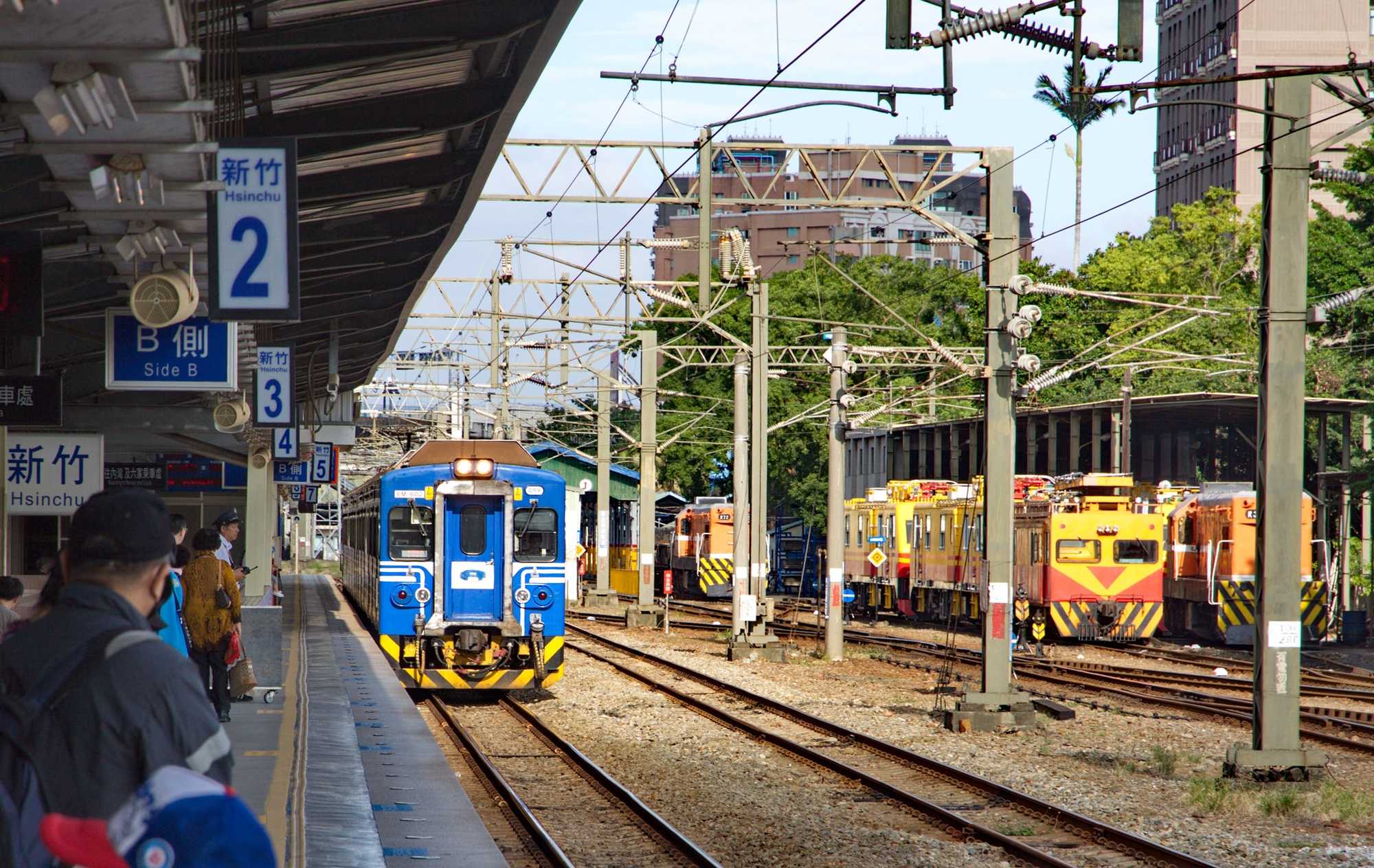 Ein Triebzug der Reihe EMU 600 und dahinter Gleisbaufahrzeuge von Plasser im Bahnhof Hsinchu an der Western Line.
