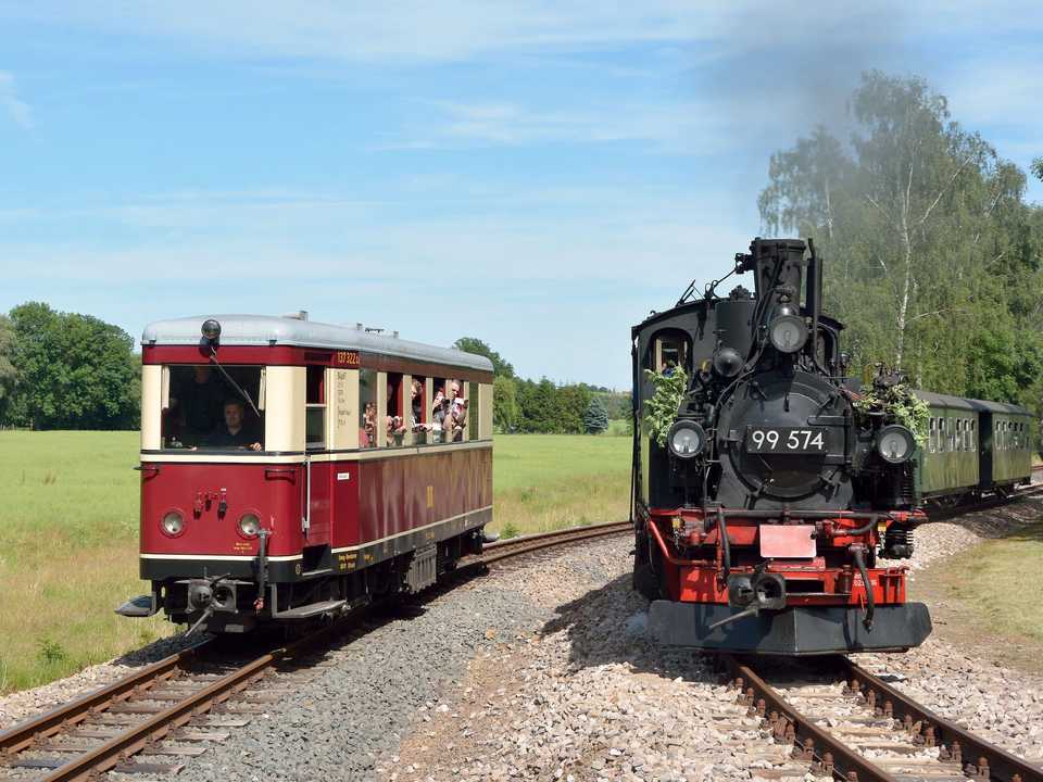 Seit dem 9.  Juni kann man mit der Döllnitzbahn wieder nach Kemmlitz reisen! Aus diesem Anlass war der Zittauer Triebwagen VT 137 322 beim „Wilden Robert“ zu Gast. Joachim Jehmlich fotografierte ihn am 11.  Juni in Nebitzschen bei der Ausfahrt nach Glossen, während 99 574 ihren Zug 268 nach Kemmlitz fuhr.