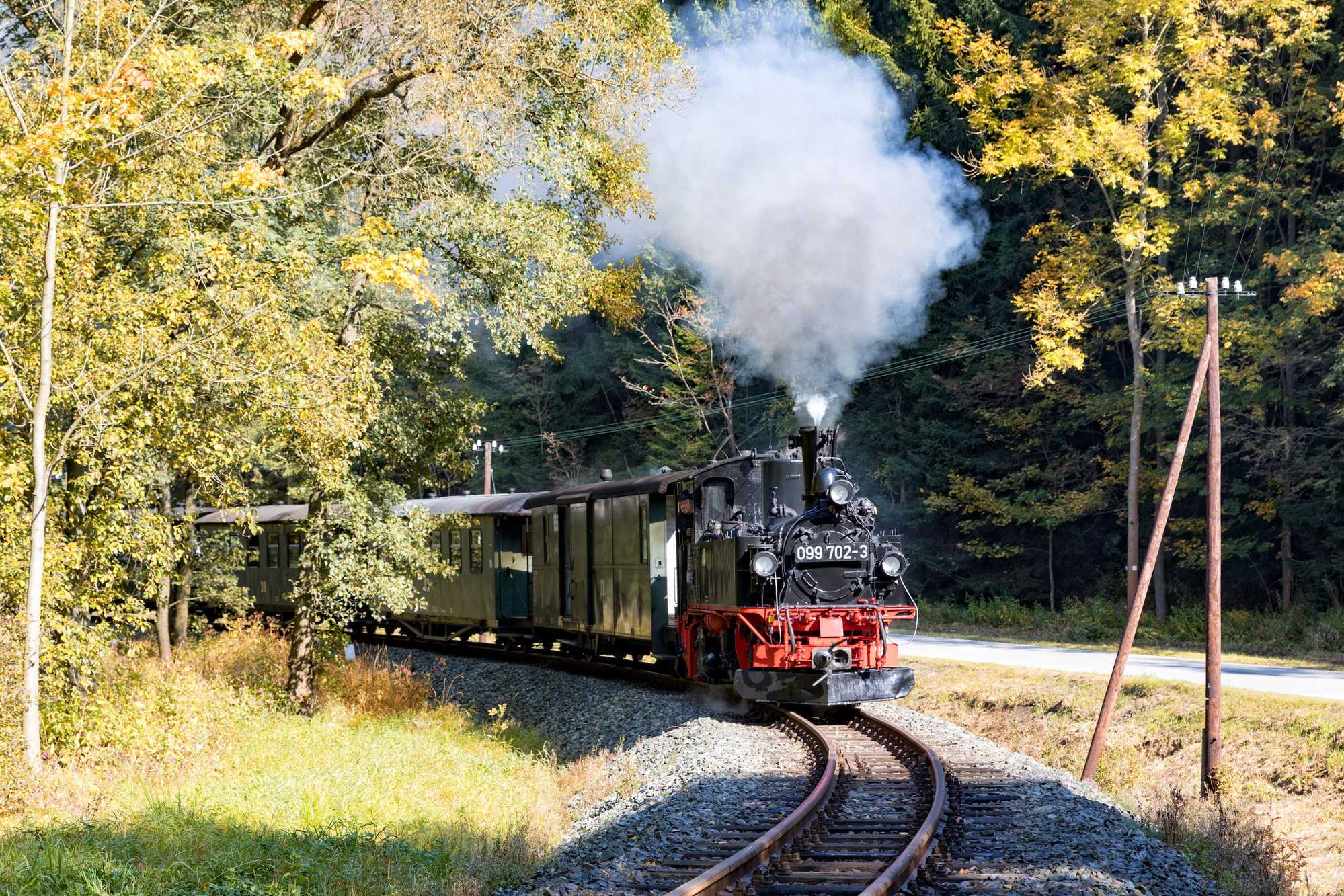 Die vier am ersten Oktoberwochenende auf der Preßnitztalbahn eingesetzten Reisezuggarnituren repräsentierten jeweils eine Epoche der Schmalspurbahn. Den Zug im Stil der 1990er Jahre führte die als 099 702-3 beschilderte 99 1542-2, hier am 30. September kurz vor dem Bahnübergang Grumbacher Straße.