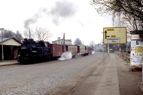 Am 14. März 1990 fotografierte Henning Struckmann die 99 2331-9 in Kühlungsborn Mitte mit straßenfahrzeugfreier Sicht auf den Zug.
Fast genauso interessant – aus geschichtlicher Sicht –ist die Litfaßsäule am rechten Bildrand mit Wahlwerbung, vier Tage vor der letzten Volkskammerwahl in der DDR.