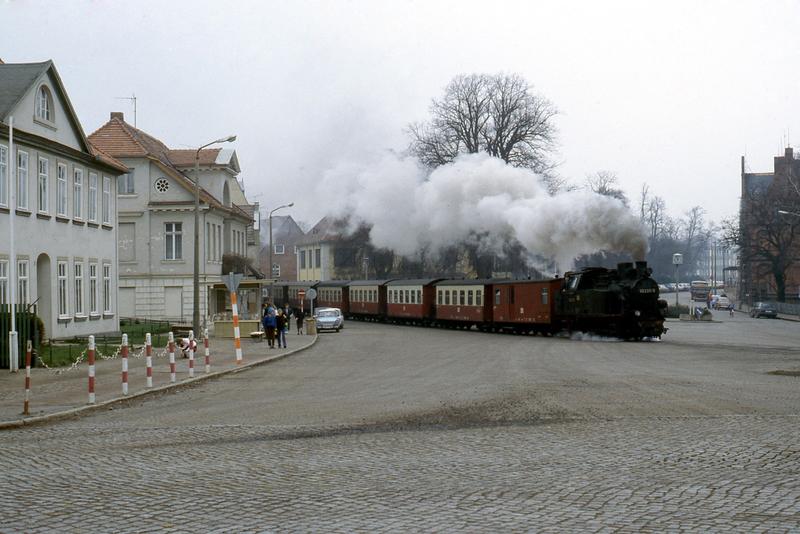 99 2331-9 überquert am 14. März 1990 bei damals noch überschaubarer Verkehrslage die zentrale Kreuzung in Bad Doberan Mitte.