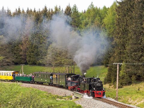 Zwei Schlepptenderlokomotiven auf 750 mm Spurweite vor einem Zug sind ein sehr seltener Anblick, der hier am 24. Mai 2015 kurz vor der Fahrzeughalle in Schlössel im Foto festgehalten wurde.