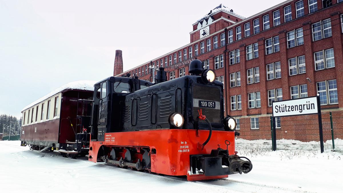 Am 15. Dezember 2018 war die Diesellok 199 051 mit dem aus Zittau geliehenen Sitzwagen 970-571 auf der Museumsbahn Schönheide unterwegs, hier im Bahnhof Stützengrün.