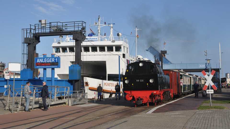 Direkt neben dem Anleger 1 für die Schiffe aus Emden in Niedersachsen und Eemshaven in den Niederlanden können die Reisenden in die Borkumer Kleinbahn umsteigen. Der Anblick der scharz/rot lackierten Dampflok 99 331 war im September eine Attraktion auf der Insel.