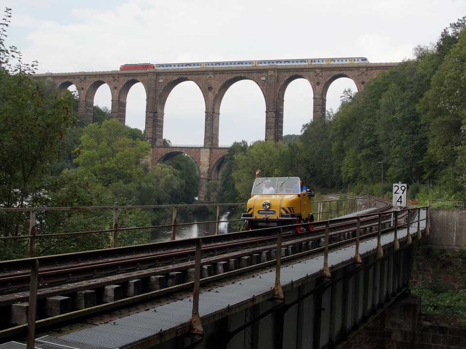 Während der von einer Diesellokomotive aus sowjetischer Produktion gezogene Zug der RegionalExpress-Linie 6 (Chemnitz – Leipzig) am 1. September 2019 die Göhrener Brücke überquerte, war ein Schienentrabi auf den Gleisen der Muldentalbahn unterwegs.