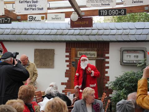 Der Weihnachtsmarkt in Lunzenau wird traditionell im September mit einem weihnachtlichen Lied eröffnet. Der Gastgeber wird dabei von seinen Gästen unterstützt. Später überreicht der Weihnachtsmann Geschenke.