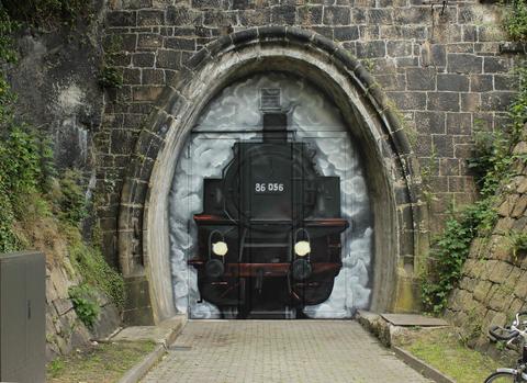 Der für den Eisenbahnverkehr nicht mehr benötigte Tunnel blieb als Lagerraum erhalten. Auf dem Tor der nördlichen Tunneleinfahrt entstand am 18. Juli 2020 dieses von Peter König aus Aue entworfene Kunstwerk. Es zeigt die Dampflok 86 056, die einst im Bw Schwarzenberg 1932 ihren Werks-
anlauf absolvierte.