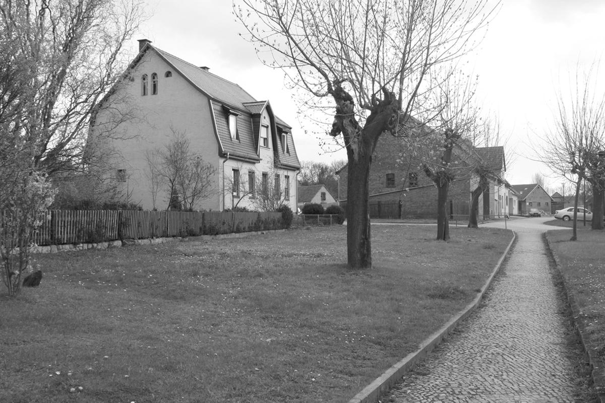 Ehemalige Trasse (zwischen Grundstück und Baumreihe) in Großbrembach. Die Scheune im Hintergrund steht auf dem ehemaligen Bahnhofsgelände.
