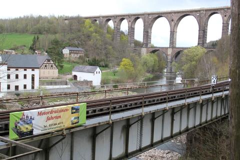 An der Brücke über den Cossener Bach wirbt nun ein Werbeplakat für die Schienentrabifahrten im Muldental.