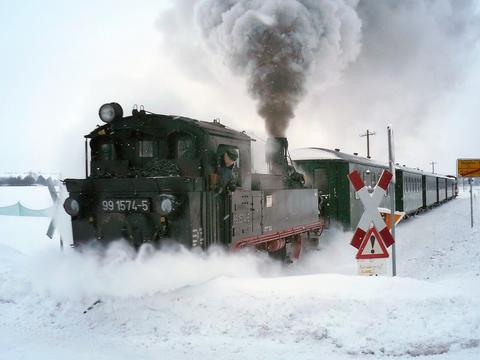 Gemeinsam mit Lok 199 030-8 (am Zugende) räumt die IV K 99 1574-5 der Döllnitzbahn am 26. Dezember 2010 nach den intensiven Schneefällen die Strecke, hier an einem Bahnübergang in Schweta.