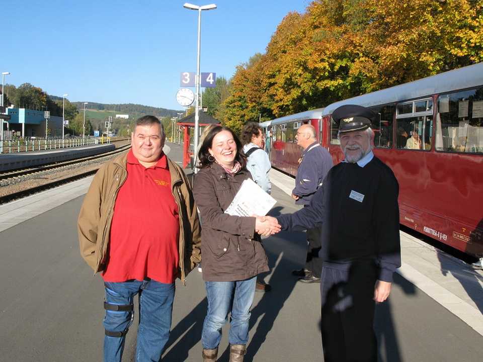 Hans-Peter Doering als Ansprechpartner der EAB und Axel Schlenkrich als Geschäftsführer des VSE begrüßten im Bahnhof Schwarzenberg den 10 000. Fahrgast der Erzgebirgischen Aussichtsbahn. Mit der Reisegruppe Weller fuhr die Dame im Oktober über die Aussichtsbahn und wieder zurück.