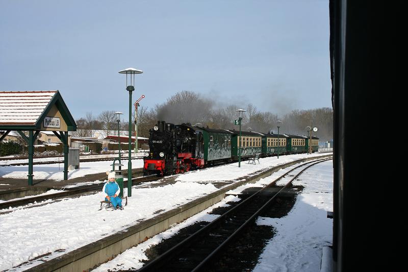 Im Winterhalbjahr setzt die RüBB oft die Dampflok 99 4632 vor den regulären Personenzügen zwischen Putbus und Göhren ein. Als diese am 1. Februar 2021 mit ihrem Fünf-Wagen-Zug nach Putbus zurückkehrte, lag auf dem Bahnsteig noch eine kleine Schneedecke.