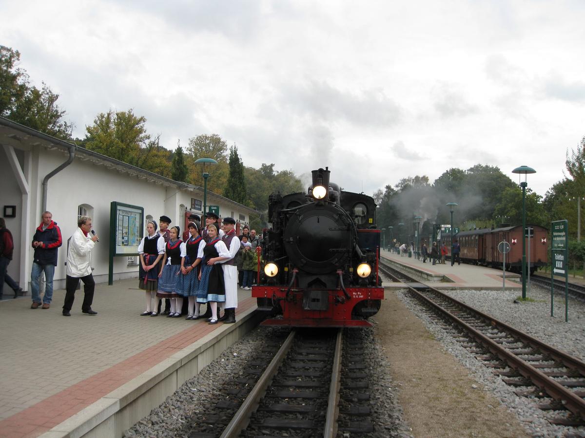 Kulturprogramm am Bahnsteig in Binz mit Lok Aquarius als Hintergrund.