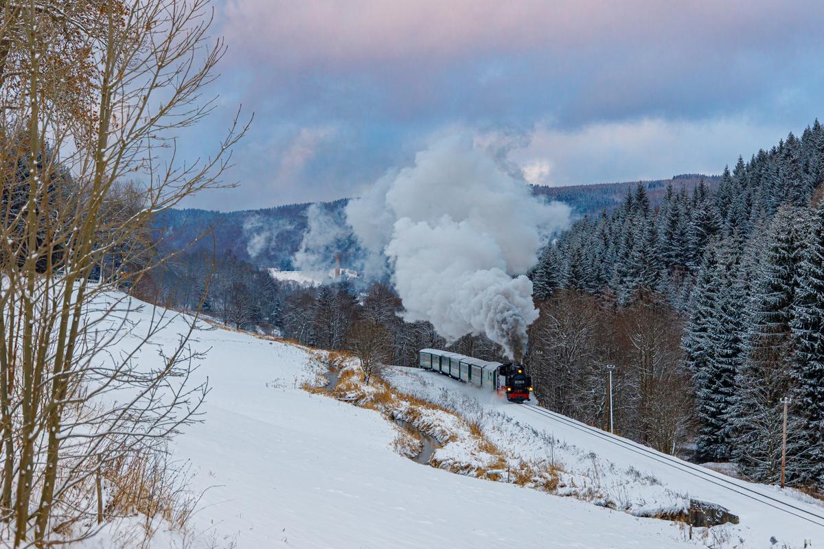 Bei Hammerunterwiesenthal fotografierte Norman Timpe am 8. Januar 2022 den von der 99 1794-9 gezogenen P 1007 der Fichtelbergbahn. Vor 25 Jahren richtete die IG Preßnitztalbahn e. V. die 100-Jahr-Feier dieser Bahn aus, im Juli 2022 begeht nun die SDG deren 125. Streckenjubiläum.