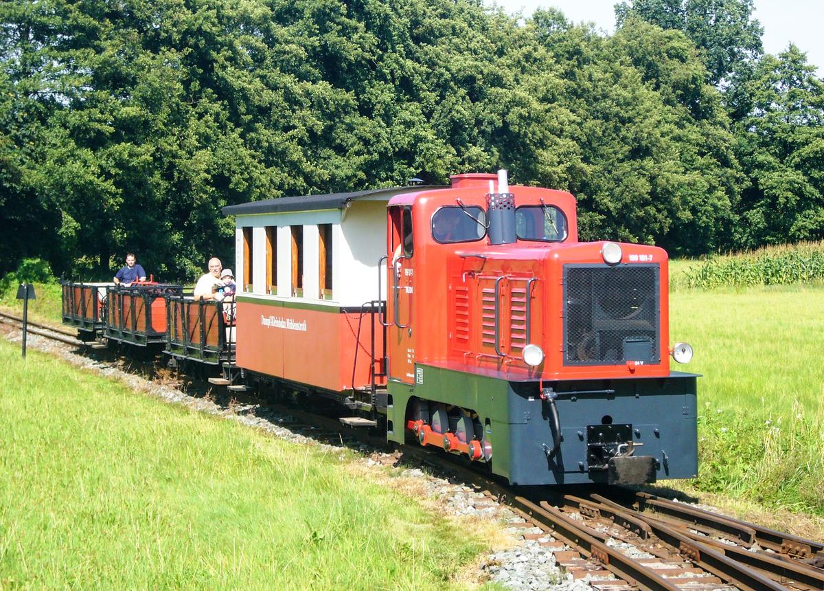 Bei der Dampf-Kleinbahn Mühlenstroth (DKBM) in Gütersloh erhielt die Berliner V10C eine rote Lackierung. Florian Rauh lichtete die Leihgabe aus der Berliner Wuhlheide auf der DKBM am 15. August 2009 mit einem Personenzug ab. Neben dem Spitzenlicht stand die Lok-Nr. 199 101-7.