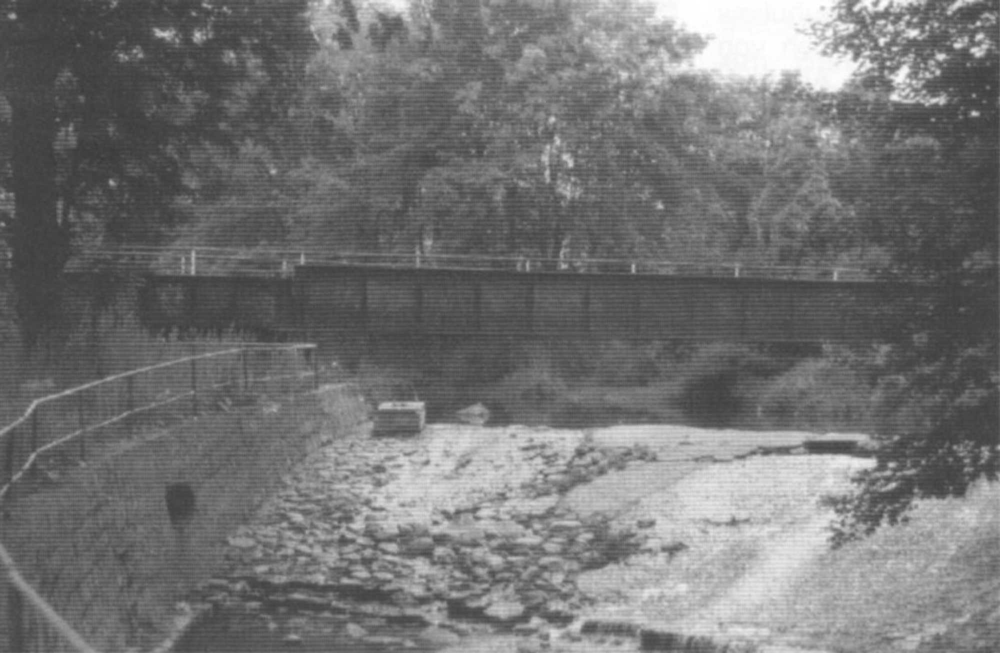 Die ehemalige Bahnbrücke über den Erlbach, im Vordergrund das Wehr.