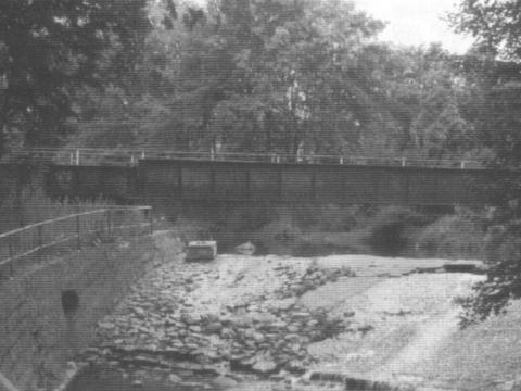 Die ehemalige Bahnbrücke über den Erlbach, im Vordergrund das Wehr.