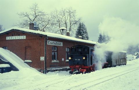 Eis und Schnee in Carlsfeld: 99 568 mit kurzem Fotozug am Sonntag, 19. Dezember 2004, vor dem Empfangsgebäude des Bahnhofs.