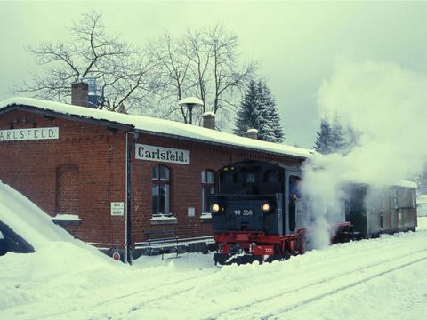 Eis und Schnee in Carlsfeld: 99 568 mit kurzem Fotozug am Sonntag, 19. Dezember 2004, vor dem Empfangsgebäude des Bahnhofs.
