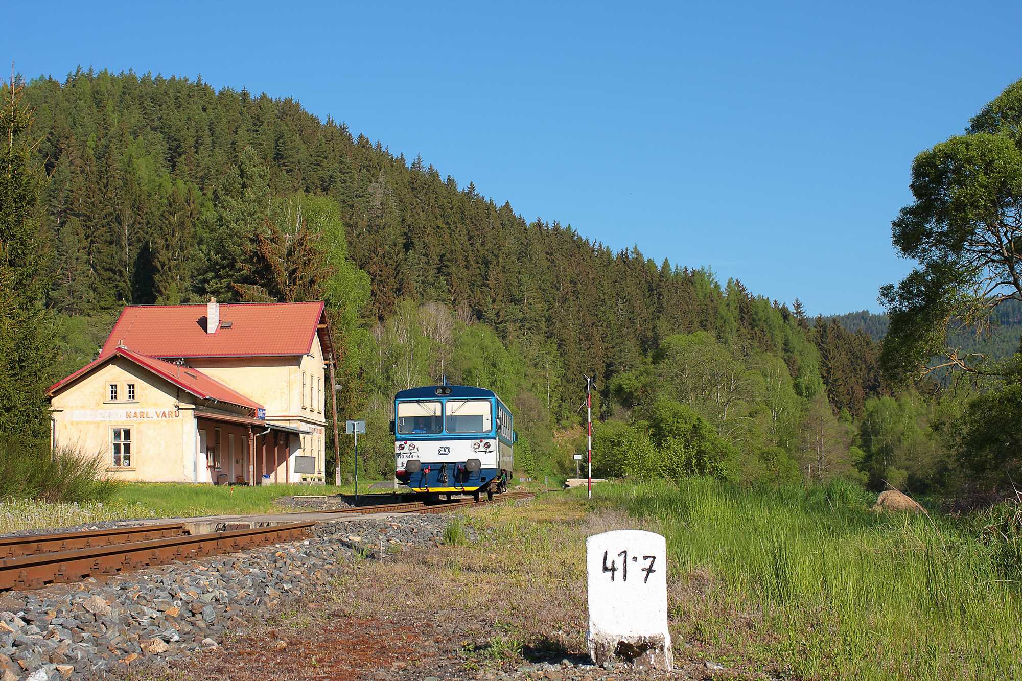 Ganz im Westen der Tschechischen Republik gibt es vom 1. Mai bis zum 31. August 2022 an den Wochenenden im Tepltal südlich von Karlsbad einen Umlauf mit einem Triebwagen der Reihe 810. Dieser verlässt 8.05 Uhr Karlovy Vary dolní nádraží (Karlsbad unt Bf) und fährt bis Krásný Jez (Schönwehr). Von dort pendelt er viermal ins sechs Kilometer entfernte Horní Slavkov-Kounice (Leßnitz). Dann fährt er 18.04 Uhr zurück nach Karlovy Vary (Ankunft 18.48 Uhr). Das Foto von Dominik Dietrich zeigt den Triebwagen 810 548 am 15. Mai 2022 im Hp Teplička u Karlových Varů (Töppeles) auf der Fahrt nach Krásný Jez.