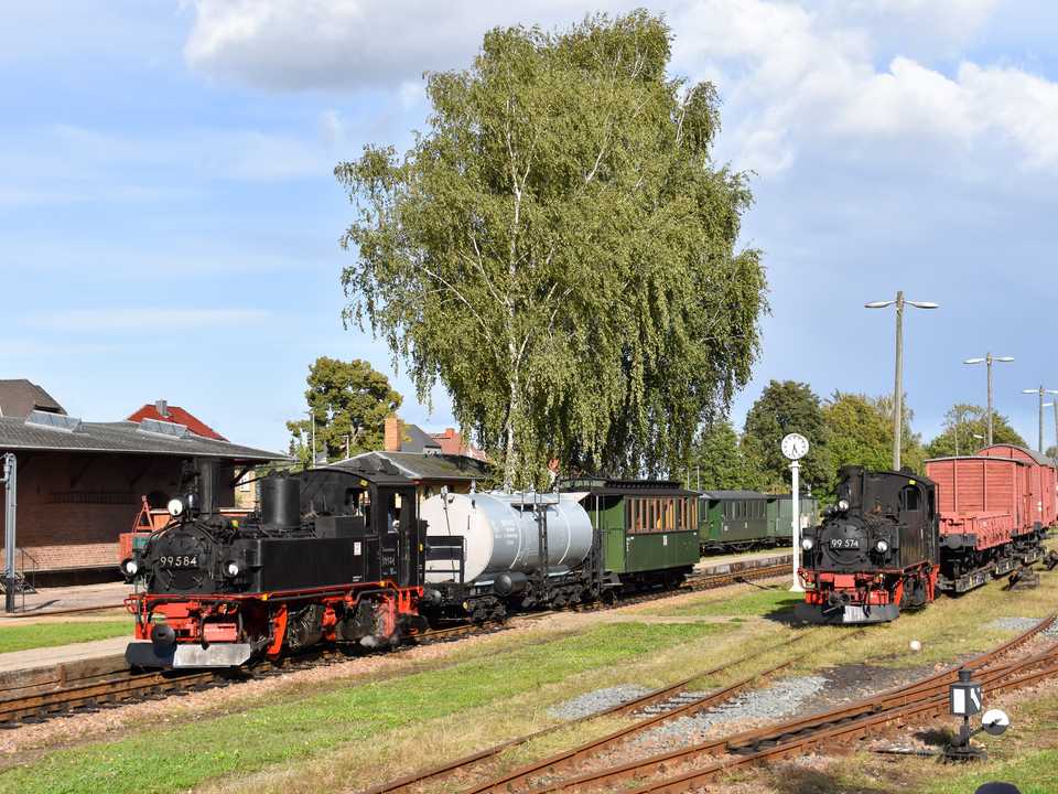 Im Bahnhof Mügeln gaben sich der von 99 584 geführte Foto-Sprengzug und ein Güterzug am 17. September 2022 dieses Stelldichein. Die nicht betriebsfähige 99 574 war dazu vor die Rollwagen rangiert worden.