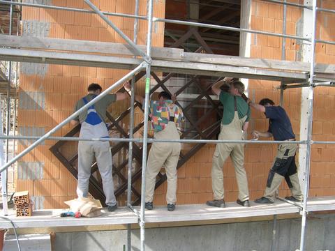 Zum Einbau der Fenster im Werkstattstand des Mehrzweckgebäudes werden acht Hände benötigt.