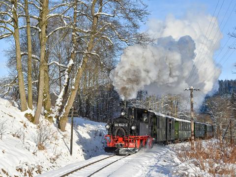 Das vierte Adventswochenende zeigte endlich einmal wieder die nicht nur bei Eisenbahnfotografen beliebte Kombination aus Sonne und Schnee, weshalb sich Thomas Poth am 17. Dezember 2022 zwischen der Ausstellungs- und Fahrzeughalle und dem Bahnhof Jöhstadt positionierte, um den P 14113 abzupassen.