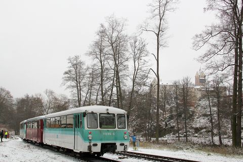 Vom Bahnhof Loket war am 3. Dezember 2022 durch die laublosen Bäume die Burg Loket (Elbogen) zu sehen. Im Vordergrund stehen die Trieb- bzw. Steuerwagen 772 312-5 + 972 771-0 + 772 367-9 aus Sachsen für die Rückfahrt bereit.