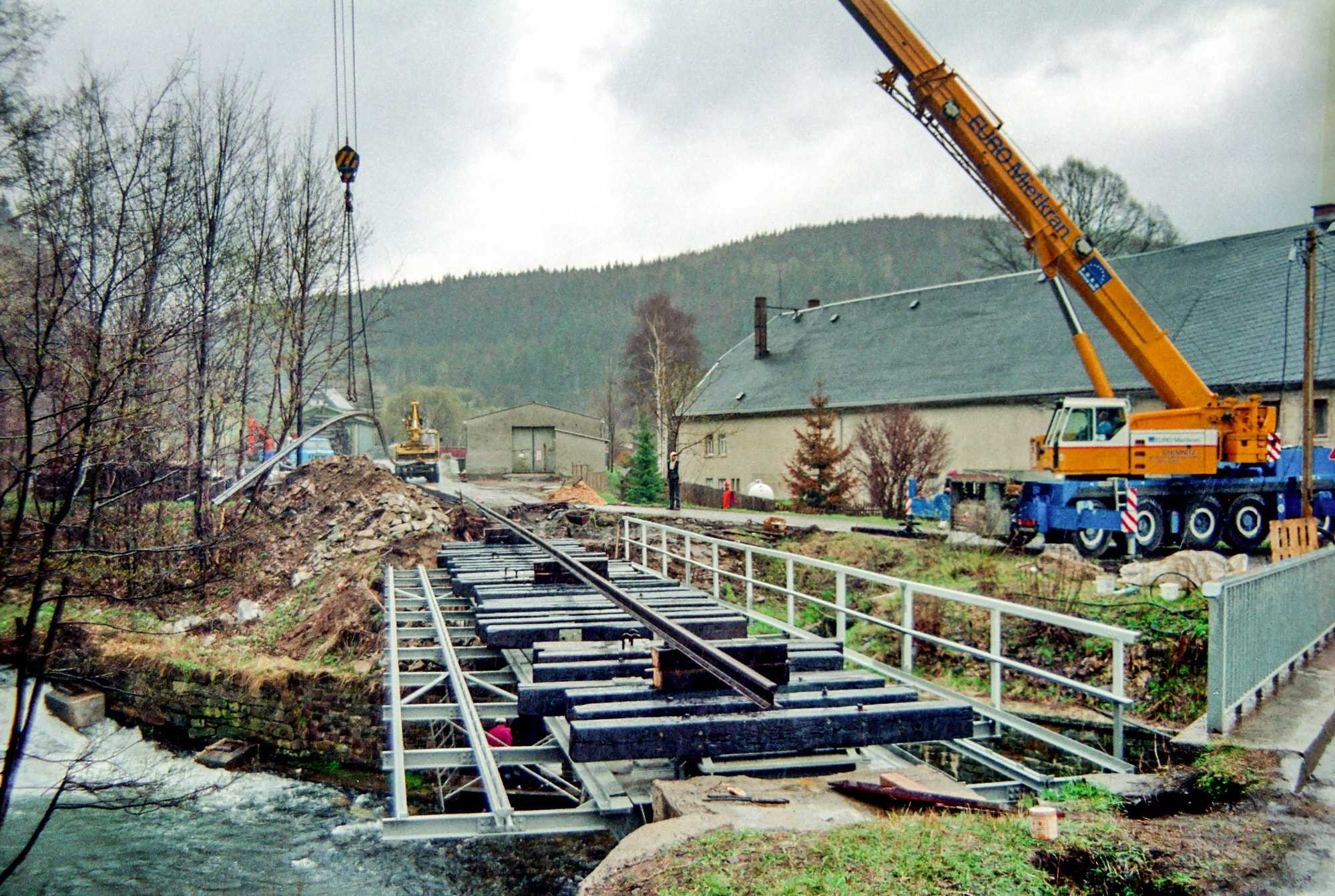 Nach dem Einheben des Brückenüberbaus am Vormittag des 3. Mai 1996 wird am Nachmittag bereits das Planum für den Bahnübergang ausge-hoben. Bis spät in die Nacht hinein wird noch an der Gleismontage gearbeitet.