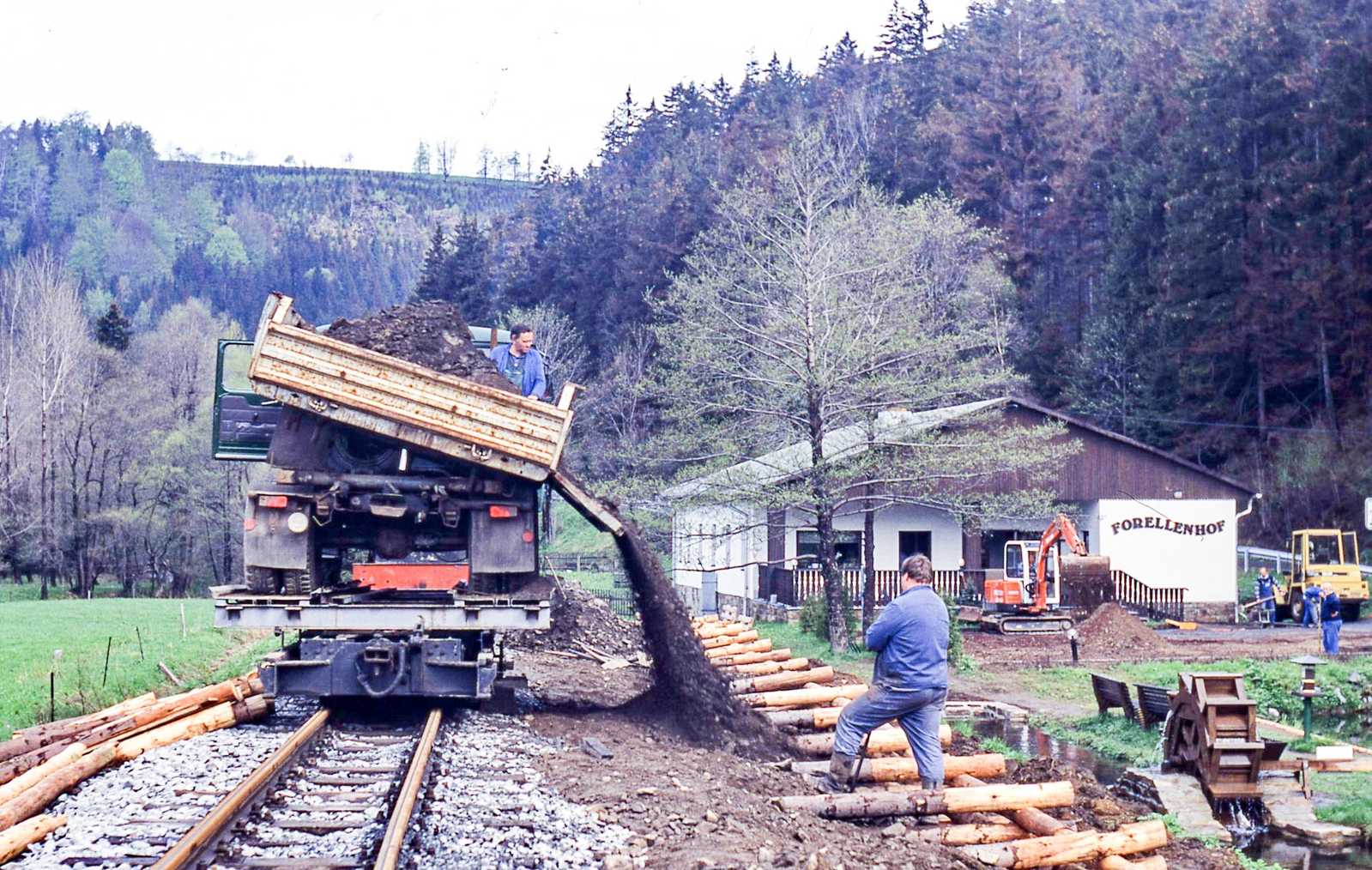 Mit W50-Seitenkipper wurde das Füllmaterial für den Bahnsteig am Forellenhof nach der Herstellung der Durchfahrt auf dem Bahnhof dann direkt aus Schmalzgrube herangefahren. Die Stämme wurden weitgehend unbehandelt als Krainerwand verbaut.